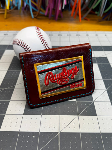Baseball with a leather patch featuring a logo on a tiled wall.